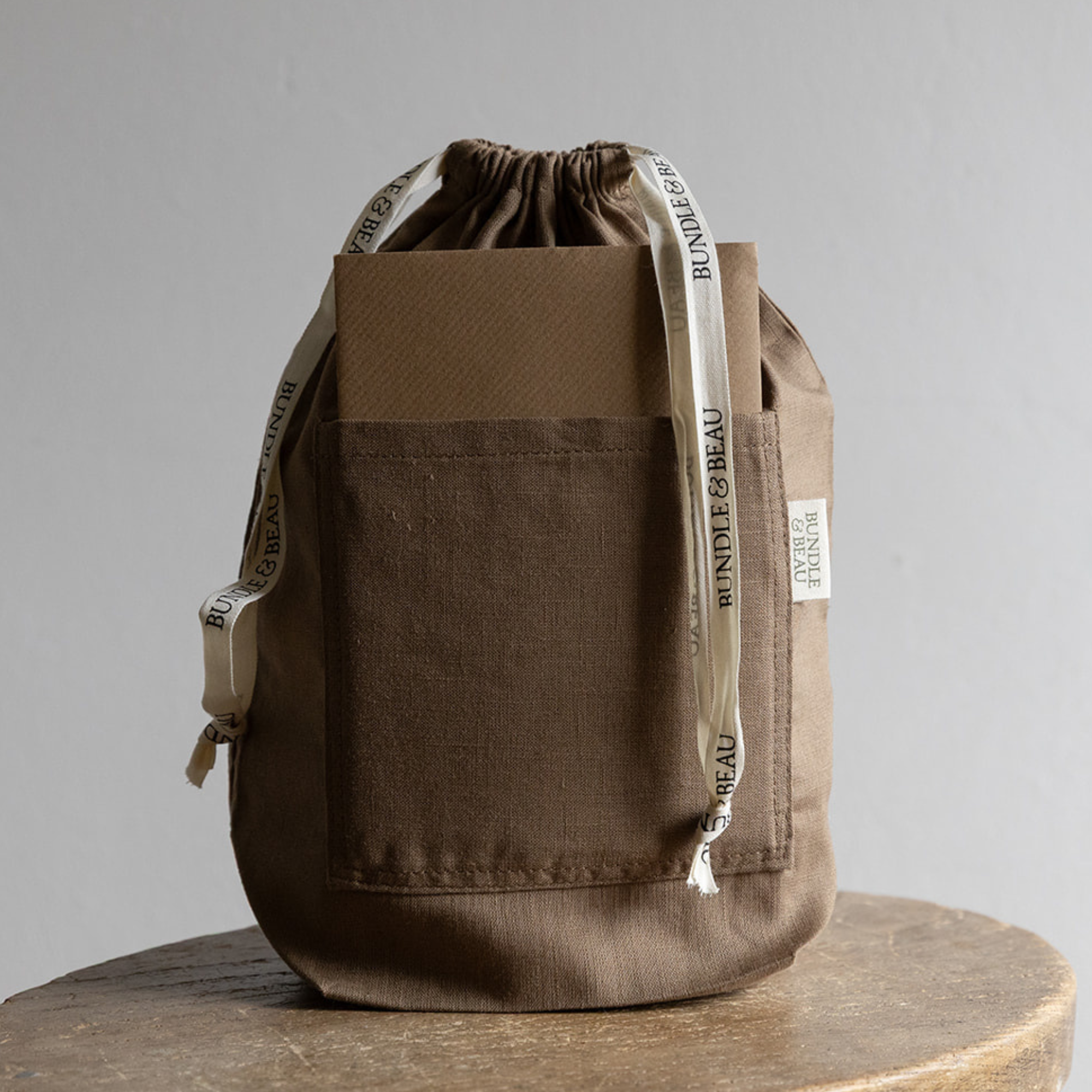 Brown drawstring bag with visible branding on a gray background