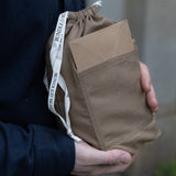 Person holding a brown drawstring bag with a visible brand label.