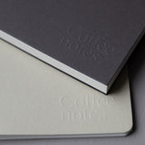 Two notebooks with 'Coffee notes' embossed on their covers, one gray and one beige.