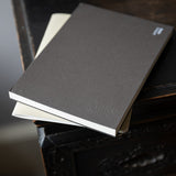 Two notebooks stacked on a dark surface