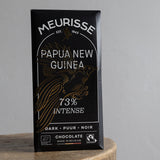 Meurisse Papua New Guinea 73% Intense dark chocolate packaging on a wooden stool with a gray background