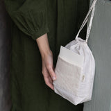 Person holding a drawstring bag against a dark background