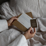 Person holding a brown envelope with a letter inside on a soft fabric background