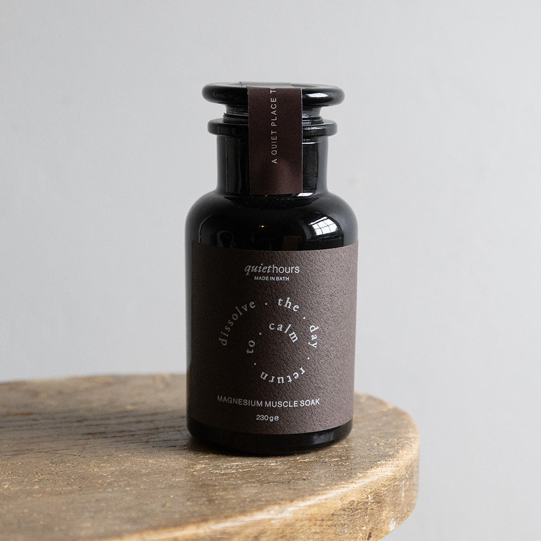 Dark brown bottle with label on a wooden stool against a light gray background