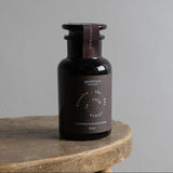 Black bottle with a label on a wooden surface against a gray background