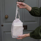 Person holding a drawstring bag with a door in the background